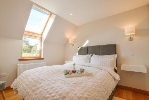 a bedroom with a large bed with a tray on it at Rowan Tree Apartment - A modern, quiet hideaway with sweeping views across Oban in Oban