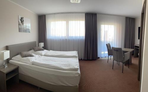 ein Hotelzimmer mit einem Bett, einem Tisch und Stühlen in der Unterkunft Hotel Neptun in Schillig