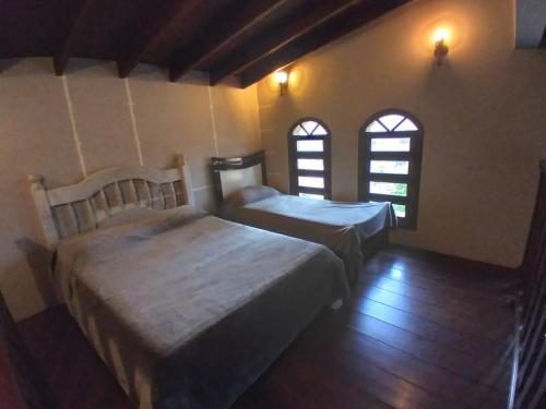 Dos camas en una habitación con dos ventanas. en Chácara do Sossego, en Piracaia