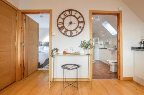 baño con encimera y reloj en la pared en Rowan Tree Apartment - A modern, quiet hideaway with sweeping views across Oban, en Oban