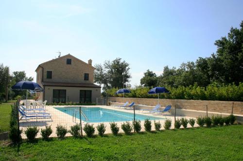 a pool with chairs and umbrellas in front of a house at Agriturismo Fara in Montegiorgio