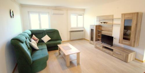 a living room with a green couch and a television at Apartmani Loli in Ugljan