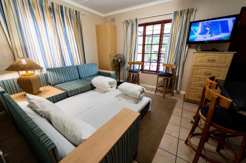 a living room with a couch and a television at Gooderson Knysna Chalets in Knysna