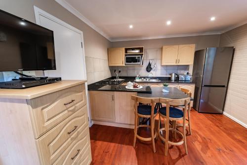 a kitchen with a table and two chairs and a television at Gooderson Knysna Chalets in Knysna