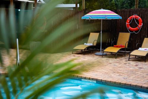 a group of chairs and an umbrella next to a pool at Gooderson Knysna Chalets in Knysna