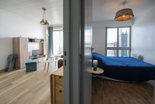 een slaapkamer met een blauw bed en een bureau bij Venez profiter de ce bel appartement situe a Saint Hilaire de Riez in La Parée Preneau