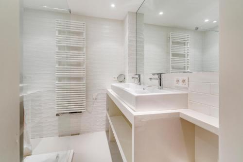 ein weißes Badezimmer mit einem Waschbecken und einem Spiegel in der Unterkunft Kindvriendelijk app met frontaal zeezicht &garage in Koksijde