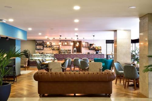 un vestíbulo con sofá y sillas y un restaurante en Tivoli Coimbra Hotel, en Coímbra