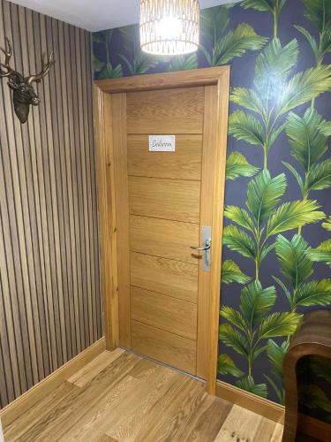 a room with a door with a tropical wallpaper at Balmaha Lodges and Apartments in Balmaha