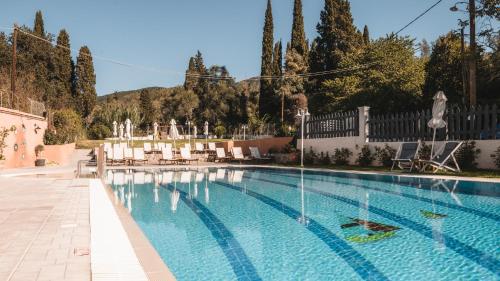 a swimming pool with a fountain in a yard at Dominoes Corfu in Ýpsos