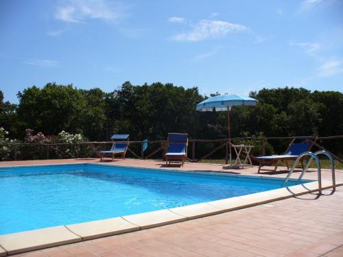 a swimming pool with two chairs and a table and an umbrella at Agriturismo Bronzivalle in Riotorto