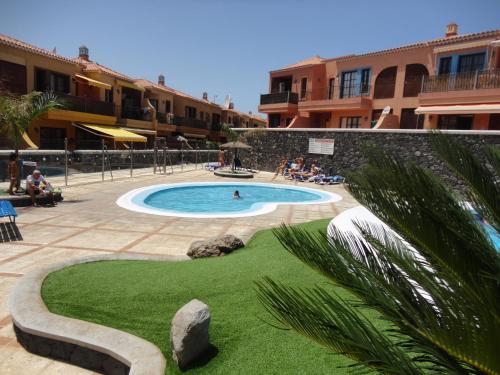 una piscina en un complejo con gente sentada a su alrededor en Residencial Atlantico I, en Costa del Silencio