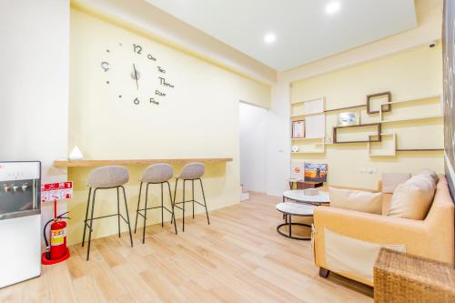 a living room with a couch and stools and a clock at WOW Penghu Homestay in Magong