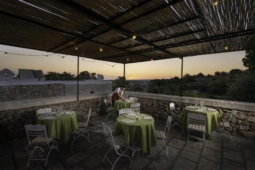 a person sitting on a patio with tables and chairs at Hotel Masseria Fontanelle in Ugento