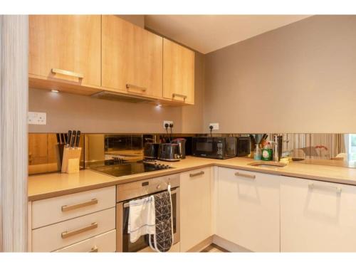 uma cozinha com armários e electrodomésticos brancos em Pass the Keys - King's Cross modern flat with Sunny Garden em Londres