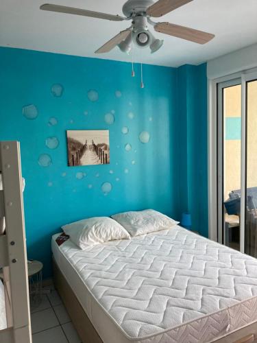 - une chambre bleue avec un lit et un ventilateur de plafond dans l'établissement Appartement T3 avec terrasse en bord de mer, à Canale-di-Verde