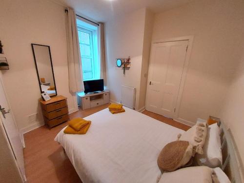 um quarto com uma grande cama branca e uma televisão em Allars Bank Apartment em Hawick