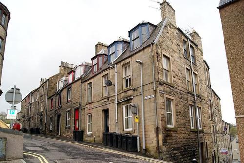 un vieux bâtiment en briques situé sur le côté d'une rue dans l'établissement Allars Bank Apartment, à Hawick