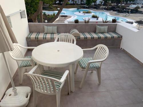 a white table and chairs on a balcony with a pool at Apartamento MIRI in Costa Teguise