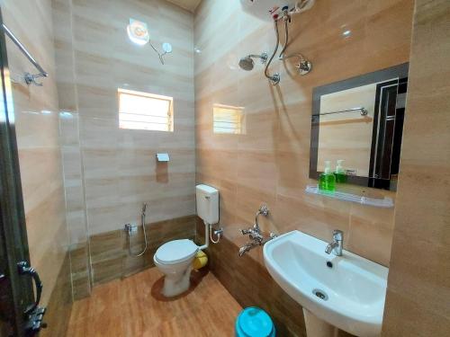 a bathroom with a sink and a toilet and a mirror at Aappayan Guest House & Restaurant in Bolpur