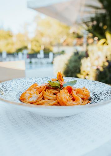 a plate of pasta with shrimp on a table at Dominoes Corfu in Ýpsos
