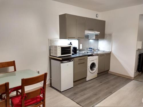 een keuken met een magnetron, een wasmachine en een droger bij Le petit nid in Montgaillard