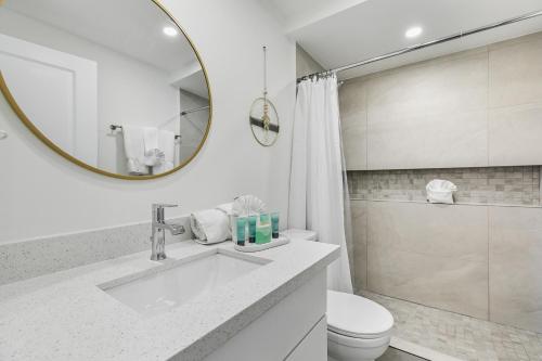 a bathroom with a sink and a toilet and a mirror at Fully Renovated Condo Steps from the Beach with Ocean View Balcony in South Padre Island