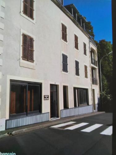 ein weißes Gebäude mit Fenstern auf der Straßenseite in der Unterkunft Studio 2 à 4 personnes avec garage privé in Le Mont-Dore