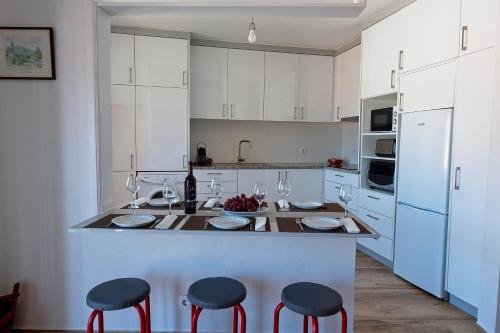 a kitchen with white cabinets and red bar stools at SeetheSea in Nazaré