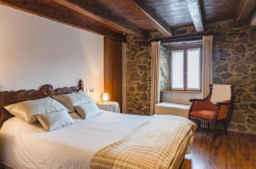 a bedroom with a large bed and a chair at 1703 CHAMBRE ET TABLE D'HOTES in Angoustrine