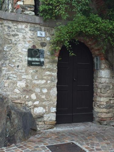 a black door in a stone wall with a sign at Washington Apartments al Vittoriale in Gardone Riviera