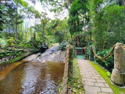 a rope bridge over a stream in a garden at Espaço Verde Novo Chalés in Teresópolis