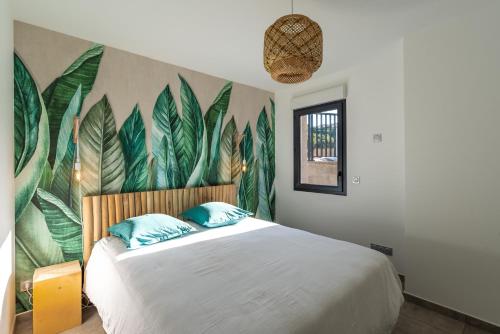 a bedroom with a bed with a mural of leaves at L'escapade Stagnola in Pietrosella
