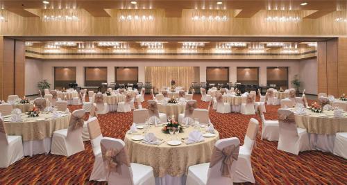 a banquet hall with white tables and white chairs at Hometel Chandigarh in Chandīgarh