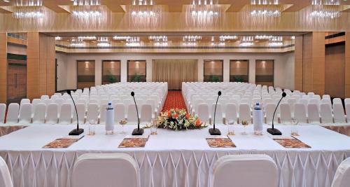 a banquet hall with white chairs and a table at Hometel Chandigarh in Chandīgarh