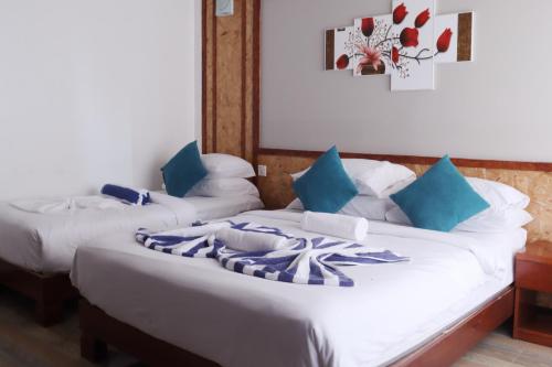 two beds in a room with blue and white pillows at Athens View Hotel in Guraidhoo