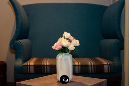 a vase of flowers on a table with a chair at R34 Boutique Guest House in Veliko Tŭrnovo