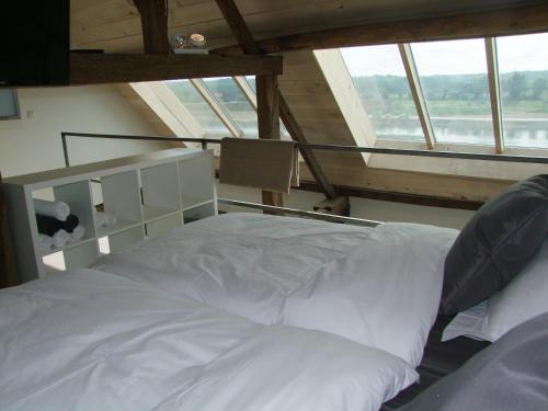 a large white bed in a room with windows at Holiday Home Janssen & Janssen in Maasmechelen