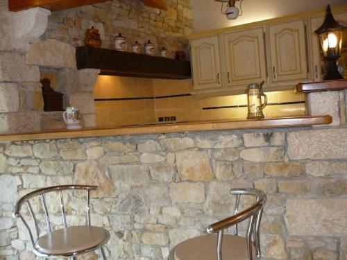 une cuisine avec deux chaises et un mur en pierre dans l'établissement Gîte dans propriété périgourdine, à Pechpialat