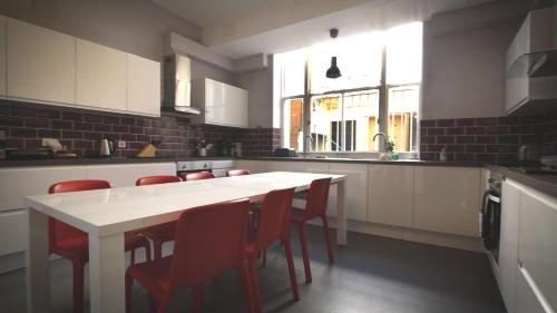 a kitchen with a white table and red chairs at Lee Abbey London in London