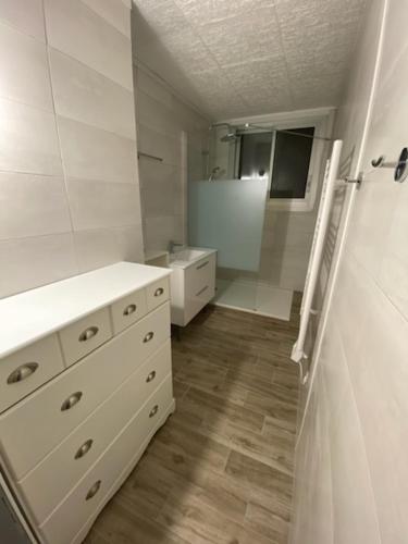 La salle de bains blanche est pourvue d'un lavabo et d'un miroir. dans l'établissement Grand appartement 3 chambres, à Perpignan