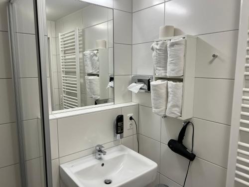 ein weißes Badezimmer mit einem Waschbecken und einem Spiegel in der Unterkunft HHotel Augsburg in Augsburg