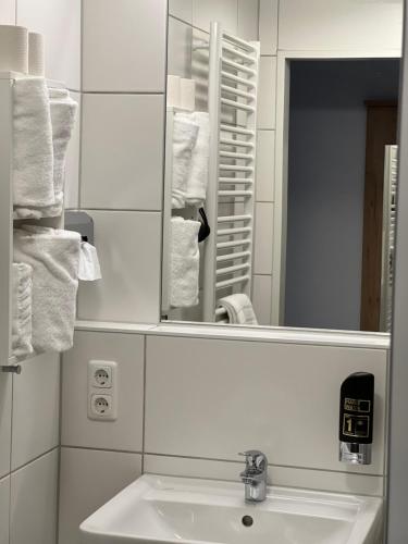 a bathroom with a sink and a mirror and towels at HHotel Augsburg in Augsburg