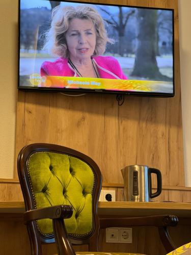 a flat screen tv hanging on a wall with a chair at HHotel Augsburg in Augsburg