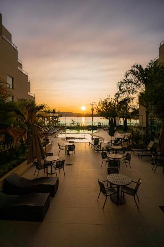 a patio with tables and chairs with the sunset in the background at eSuites Lagoa Santa in Lagoa Santa