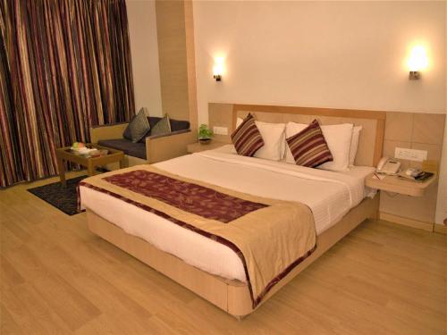 a hotel room with a large bed and a chair at IRA By Orchid Bhubaneswar in Bhubaneshwar