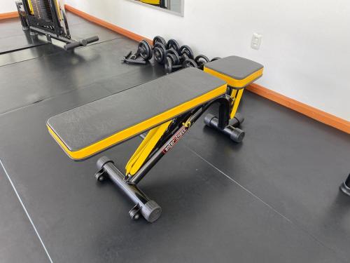 a gym with a yellow bench and weights at Executivos Hotel in Cruz Alta