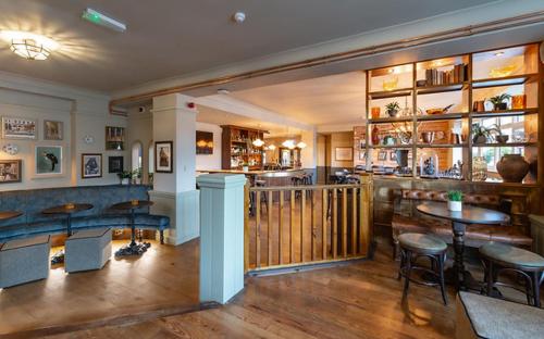 uma sala com mesas e cadeiras e um bar em The Bear em Bath