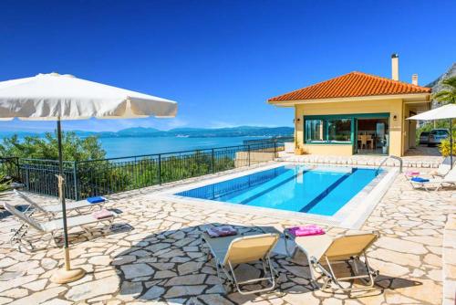 a house with a swimming pool and an umbrella at Villa Theaya in Nisakion