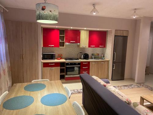uma cozinha com uma mesa de madeira e armários vermelhos em IGI RED FLAT with free private parking em Cluj-Napoca